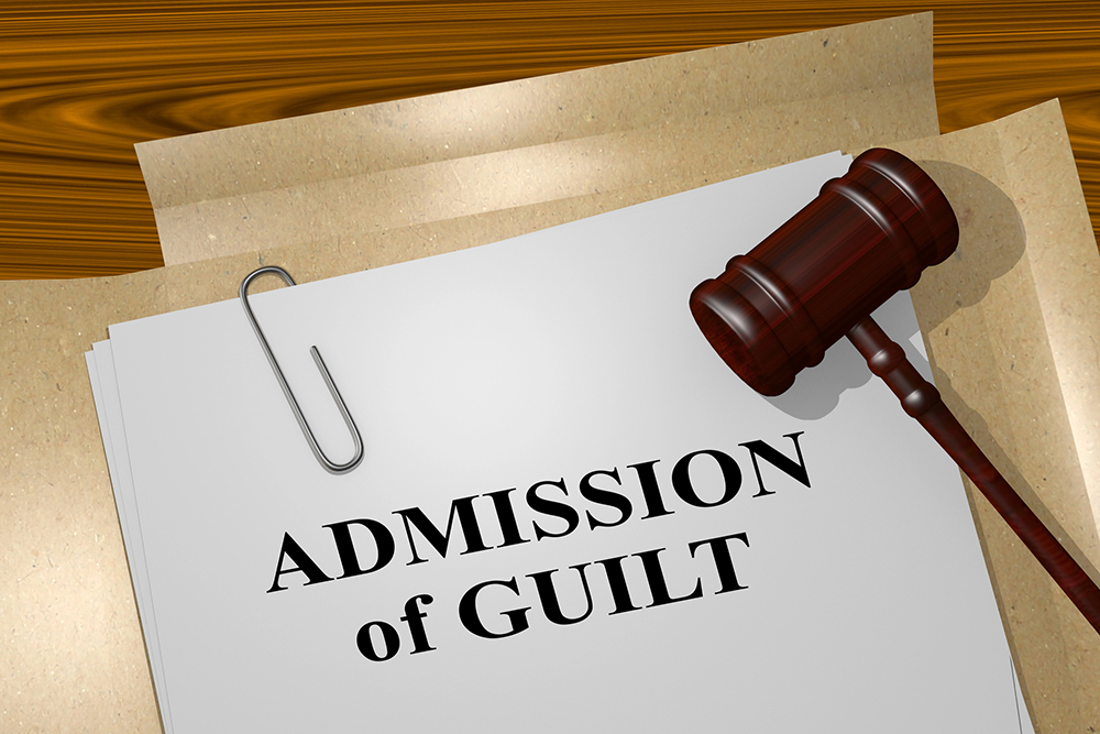 Gavel resting beside a document titled 'Admission of guilt' on a wooden desk surface.﻿?﻿